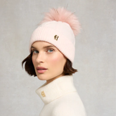 Woman wears a soft pink beanie hat on a grey background